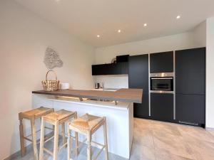 a kitchen with black and white cabinets and stools at Woonhuys in Riemst