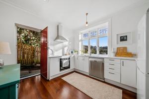 een keuken met witte kasten en een groot raam bij Capital Charm - Wellington Holiday Unit in Wellington