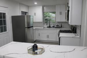 a kitchen with white cabinets and a stainless steel refrigerator at Cozy House Downtown Houston! in Houston