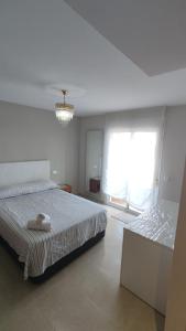 - une chambre blanche avec 2 lits et une fenêtre dans l'établissement HABITACIONES CACHEMIRES en ALMERIA, à Almería