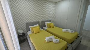 two beds in a small room with yellow sheets at Casa da Posa - AL - Férias com Piscina , Natureza e Perto do Centro de Ponte de Lima in Ponte de Lima