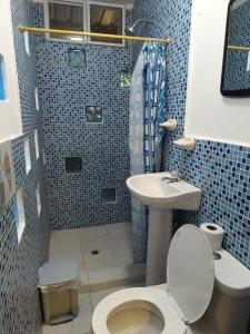 a blue tiled bathroom with a toilet and a sink at Casa Shangri La in Canoa