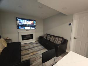 ein Wohnzimmer mit einem Sofa und einem Flachbild-TV in der Unterkunft Cozy 2 Bedroom Suite, Queen Beds, Near the Airport in Edmonton