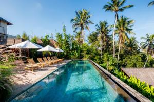 a swimming pool with chairs and umbrellas next to a resort at LeRosa Valley Resort in Ubud