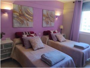two beds in a room with purple walls at Las Palmeras, 893 in Fuengirola