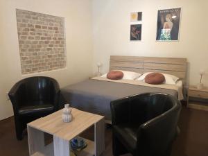 1 Schlafzimmer mit einem Bett, 2 Stühlen und einem Tisch in der Unterkunft Apartman Reduta in Lučenec
