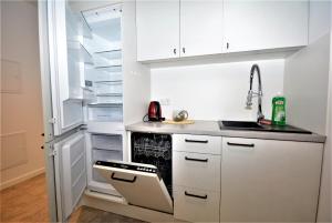 a kitchen with white cabinets and an open refrigerator at Studio Pieskowa Skała in Warsaw