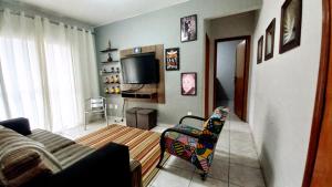 a living room with a couch and a tv at Apartamento na Praia Grande in Praia Grande