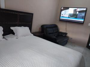 een slaapkamer met een bed en een stoel en een flatscreen-tv bij WAKEUP FRESH GUEST HOUSE in Johannesburg