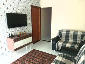 a living room with a tv and a chair at Casa Aurora da Chapada in Mucugê