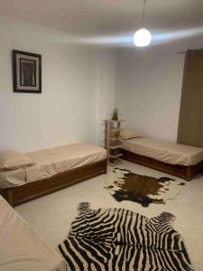 Habitación con 2 camas y alfombra de cebra en el suelo en Appartement 5 lits climatisé salon 2chambres cuisine équipée SDB en Staoueli