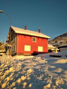 een rood gebouw met sneeuw ervoor bij Cocon lumineux près des pistes in La Bresse