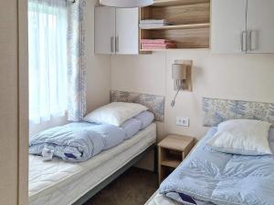 2 camas en una habitación pequeña con ventana en Holiday home Tansøy, en Tansøy