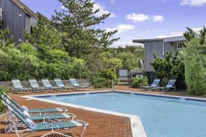 a swimming pool with lounge chairs next to a house at Unit 1723 Ocean Colony Beach in Amagansett +26 photos