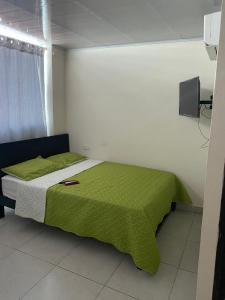 a bedroom with a bed with a green blanket at Hotel Gloria Del Norte in Cartagena de Indias