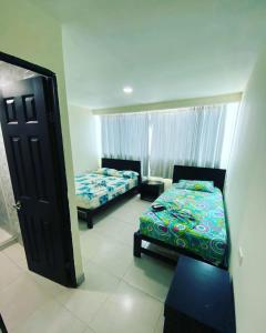 1 dormitorio con 2 camas y puerta abierta en Hotel Gloria Del Norte, en Cartagena de Indias