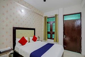 a bedroom with a bed with red and blue pillows at Shree Hotel in Lucknow