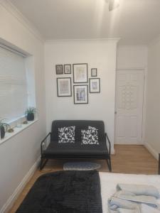 uma sala de estar com um sofá preto e quadros na parede em Manhattan Studio flat northbridge services em Londres