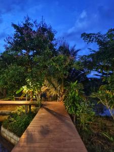 a wooden pathway with trees and a blue sky at Nakhokyor Farm in Ko Yao Yai