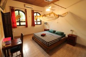 a bedroom with a bed and a table and windows at Serenity Eco Guesthouse - CHSE certified in Canggu