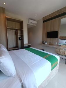 a bedroom with a large white bed and a television at DEJAVU 2.0 HOTEL BAJO KOMODO in Labuan Bajo