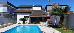 una villa con piscina di fronte a una casa di Lindo Sobrado com Piscina em Condomínio Fechado a Bertioga