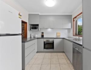 a large kitchen with white cabinets and a window at The Entrance 2Beds Holiday House in The Entrance