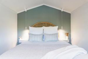 a bedroom with a large white bed with blue walls at Flaxpod Cabin in Raglan
