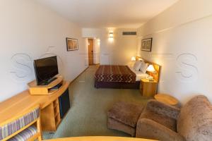 Hotel Alphaville Apto 1405 في باروري: غرفة فندق بسرير وتلفزيون