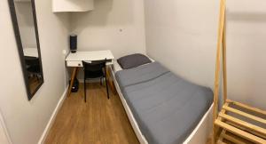 Habitación pequeña con cama y escritorio. en Gup Hostel en Curitiba