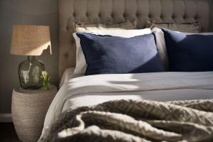 a bed with blue and white pillows and a lamp at Quartz Retreat in Daylesford