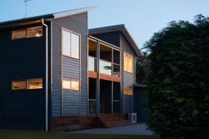 a modern house with glass windows and a tree at Quartz Retreat in Daylesford