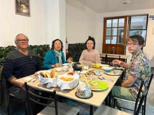 een groep mensen die rond een tafel eten bij Marluc Casa de Descanso in Machu Picchu