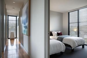 a bedroom with two beds and a hallway with windows at Ridge House in Hepburn Springs