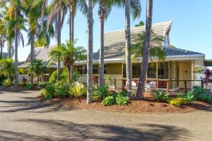 uma casa com palmeiras em frente em ULTIQA Village Resort em Port Macquarie