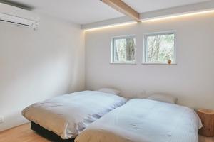 Duas camas num quarto branco com duas janelas em ECHO em Yonezawa