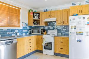 cocina con armarios de madera y nevera blanca en The Perfect Holiday Home en Sussex inlet