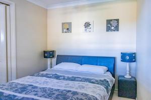 a bedroom with a blue bed with two blue lamps at The Perfect Holiday Home in Sussex inlet