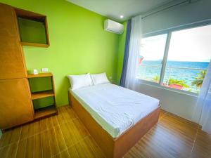 a small bedroom with a bed and a window at Ocean View Guest House, Mabini in Batangas City