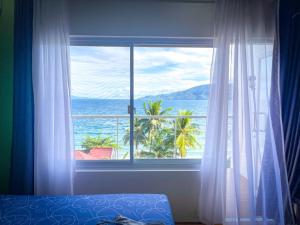 a bedroom with a window with a view of the ocean at Ocean View Guest House, Mabini in Batangas City
