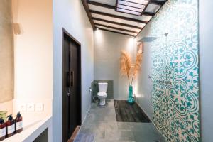 La salle de bains est pourvue de toilettes et d'un mur bleu et blanc. dans l'établissement Coconut Garden Resort, à Gili Trawangan