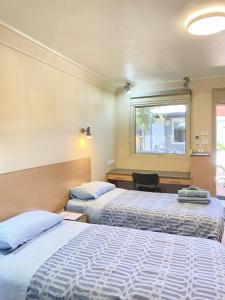 1 dormitorio con 2 camas y ventana en Econo Lodge Karratha, en Karratha