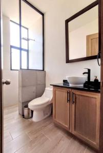 a bathroom with a toilet and a sink and a mirror at Casa San Sebastián - San Miguel de Allende in San Miguel de Allende