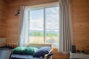 富良野市にあるFurano Log House Farm Resortのフィールドビューの窓付きのベッドルーム