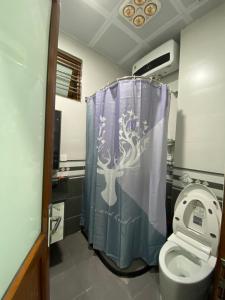 a bathroom with a toilet with a tree shower curtain at Tiny home 小角落 in Tam Ðảo