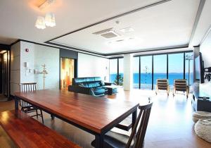 ein Wohnzimmer mit einem großen Holztisch und einem Wohnzimmer in der Unterkunft CF Pension in Pohang