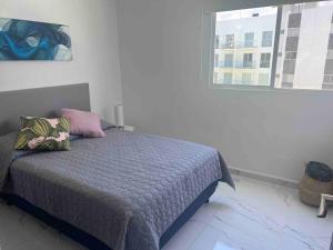- une chambre avec un lit doté de draps violets et une fenêtre dans l'établissement Hermoso departamento en Acapulco, à Acapulco