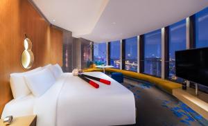 a hotel room with a white bed and a flat screen tv at W Shanghai - The Bund in Shanghai