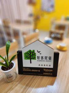 a sign sitting on top of a table with a plant at Lang duo duo Homestay in Huxi