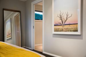 a bedroom with a painting of a tree on the wall at Schafhalle in Hepburn Springs